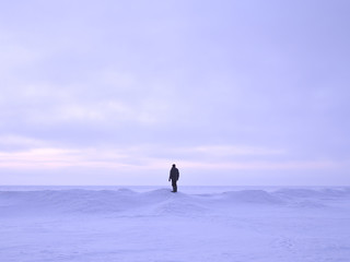 Fototapeta na wymiar Man standing on a small iceberg by the frozen snow covered sea.