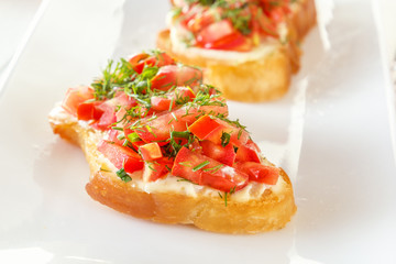 Bruschetta with fresh tomatoes and cheese on a white plate. Close-up