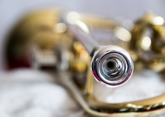 Artistic close up of the brass musical instrument, trumpet, focus on the mouthpiece, the rest of the instrument is blurry 