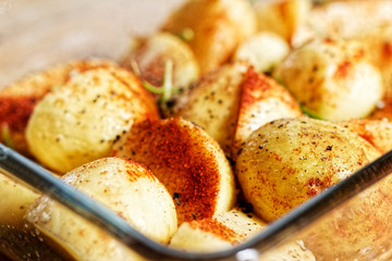 Potatoes in spices in the glass vessel prepared to be baked 