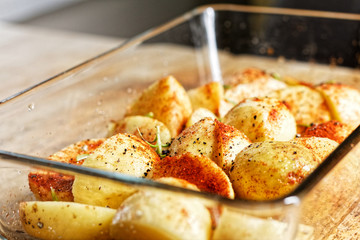 Potatoes in glass vessel and spicies on it (chili and rosemary) prepared to be baked or roasted