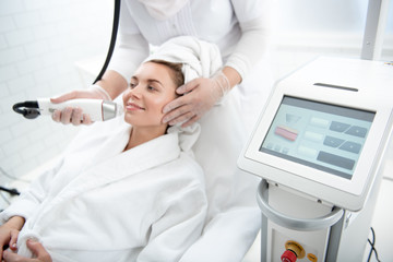 Portrait of beaming girl having professional rejuvenation of face in beauty salon. Treatment concept