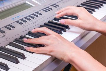 Obraz premium Hands of a young girl next to the piano keys. The girl plays the piano. Performing a musical piece on a piano_