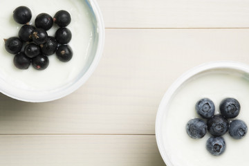 Yoghurt with berries. Blueberries and currants in yoghurt on a table. Top view, flat lay. Healthy breakfast