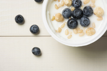 Yoghurt with berries. Blueberries and nuts in yogurt on a table. Top view, flat lay. Healthy breakfast