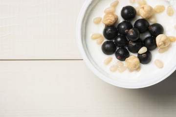 Yoghurt with currants and nuts on a table. Top view, flat lay. Healthy breakfast