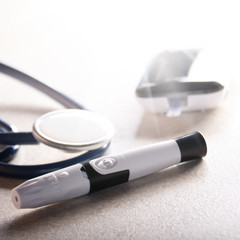 Personal blood glucose meter and lancet with stethoscope on the table