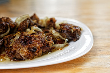 Fried chicken's livers on white plate on a wooden table