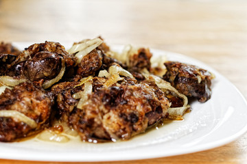 Fried chicken's livers on white plate on a wooden table