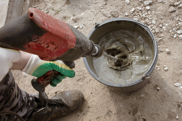 Obraz premium The worker mixes the concrete mixture at the construction site