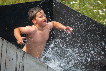 A boy is swimming in the pool with a spray