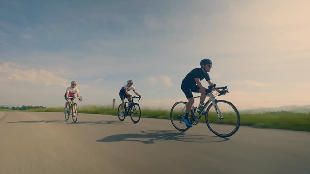 Close up, low angle, tracking shot of cyclists on countryside road