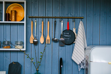 Cooking utensils hanging on wooden wall in the kitchen. Transparent glass jars for grain