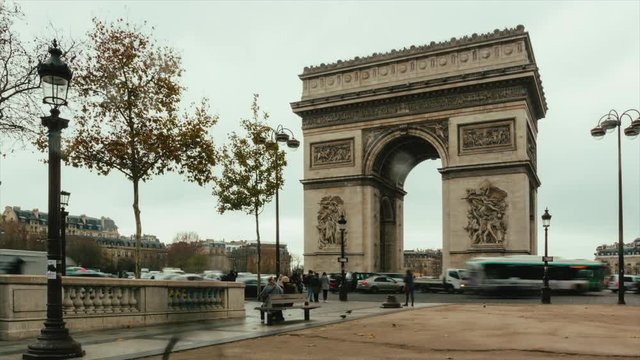 Street traffic time lapse near Arc de Triomphe on cloudy day at rush hours in Paris, France. Cityscape, city life, famous touristic places and landmarks in Europe. Transportation and tourism concept