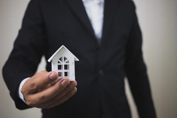 Businessman hand holding model white house. Property investment and house mortgage financial concept, Home protect, Insurance. With copy space for your text.