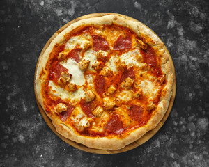 Home made rustic pizza with salami and chicken topped with melted mozzarella cheese