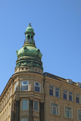 Fototapeta na wymiar Copenhagen, Denmark - view of an antique building tower in city center with the green copper decorated cover characteristic of the city profile