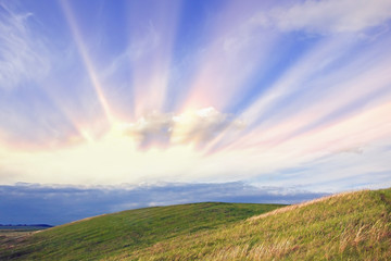 amazing summer landscape with green hills and blue sky and clouds with sun rays