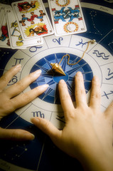 Astrologer, fortune teller with astrology background withd zodiac signs, pendulum and tarot tarots...