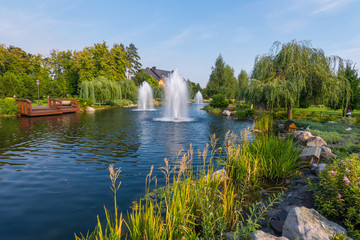 three high fountains on a lake with weeping willows on the banks