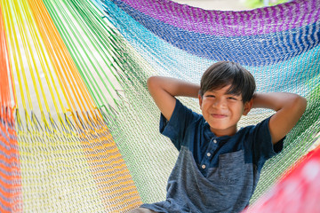 The little boy sitting at the hammock and he so happy