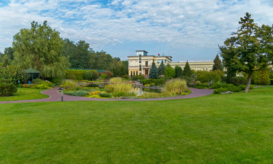 A beautiful decorative lake with a huge number of different shrubs and decorative flower beds in the background of a modern building