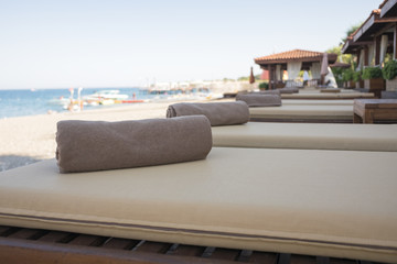 Sun loungers with towels on the beach by the sea.