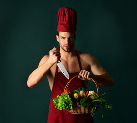 Bearded male chef holds basket with vegetables and knife. Professional food preparation concept. Man in cook hat and apron with knife. Food. Preparation concept. Chef holds basket with vegetables.