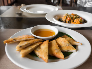 close up of crispy spring roll stuffed with prawns and pork on a white plate in a restaurant