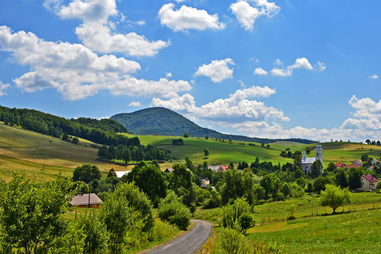 View of  grass fields,  church in Izby village and mountain Lackowa (997 msl) in Low Beskid (Beskid Niski), Poland
