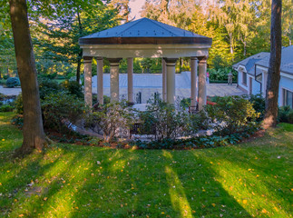 A large arbor for rest with columns supporting the roof with benches and a table inside. Located in...