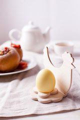 Easter breakfast or lunch - boiled egg in a wooden stand, tea and baked apples on a light background, Provence