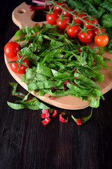 Chopped chard leaves on a cutting board and cherry tomatoes next to it