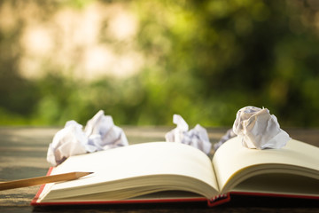 Concept idea. Open vintage book with crumpled papers ball and pencil. Copy space for your text. Conceptual great ideas are always available. Creative thinking.