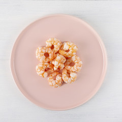 Boiled shrimp on a pink plate. Macro. The concept of healthy eating. The background is white. Copy space. Square shot. Top view.
