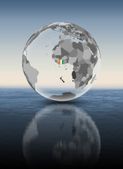 Ivory Coast on translucent globe above water