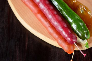Churchkhela with varying berry glazing on a wooden board. Georgian cuisine dessert