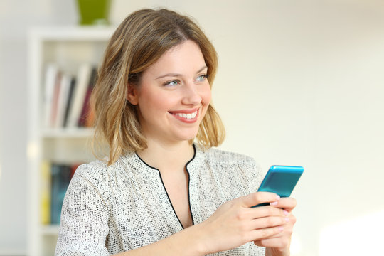 Happy woman looking at side holding a mobile phone