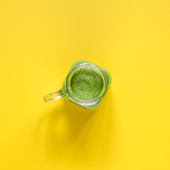 Freshly prepared green smoothie on yellow background