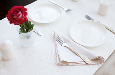 Romantic dinner concept. Valentine day or proposal background. Top view of restaurant wooden table with heart and rose with cutlery on plate. Copy space on rustic wood