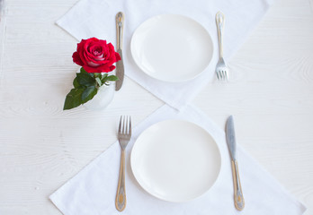 Romantic restaurant table setting for two with roses plates and cutlery