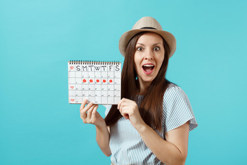 Portrait of young woman in blue dress, hat holding female periods calendar for checking menstruation days isolated on trending blue background. Medical healthcare, gynecological concept. Copy space.