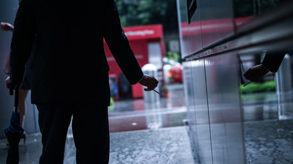 Businessman smoking after stress break from work in office, busy raining city
