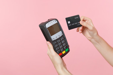Close up cropped photo of female holding in hands wireless modern bank payment terminal to process and acquire credit card payments, black card isolated on pink background. Copy space for advertising.