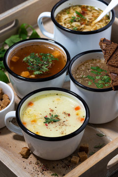 hot soups in mugs on wooden tray, vertical