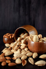 Peeled and unpeeled almond nuts in wooden bowls