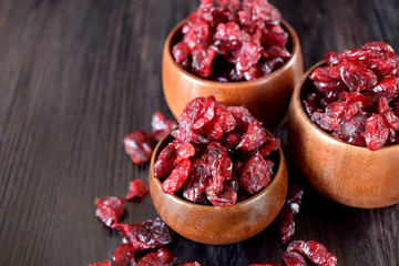 Dried cranberries in wooden bowls against the dark background