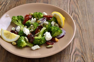 Salad with broccoli, dried tomatoes, feta, onions and pumpkin seeds, copy space