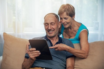 happy senior couple using digital tablet at home