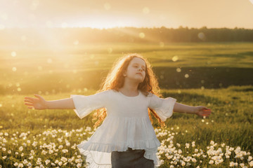 Curly hair girl closed her eyes and breathing with fresh blowing air on meadow outdoors.